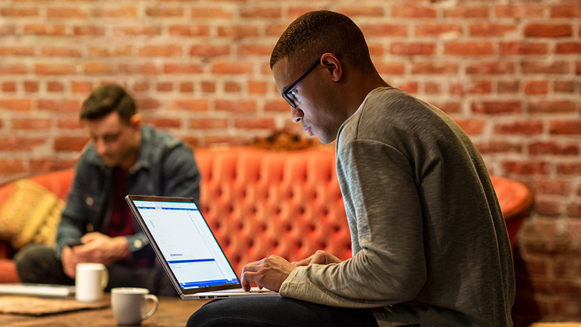 Male developer works remotely from a cafe.