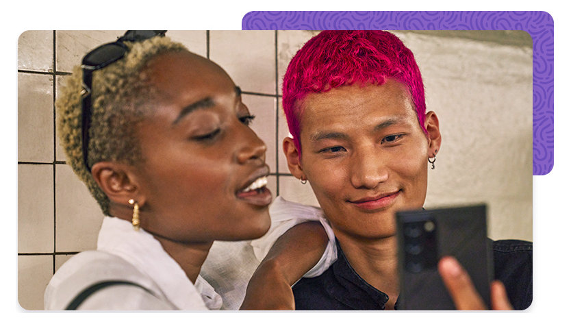 Two colleagues, smiling, looking at a phone screen