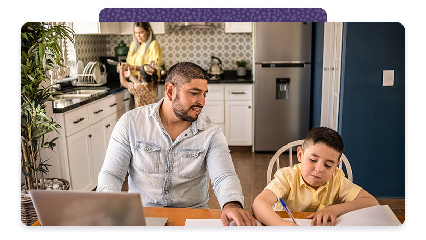 A man and a boy work together at a kitchen table. 