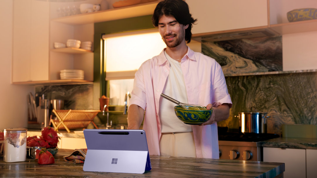 A man standing at a kitchen counter using a Surface Pro