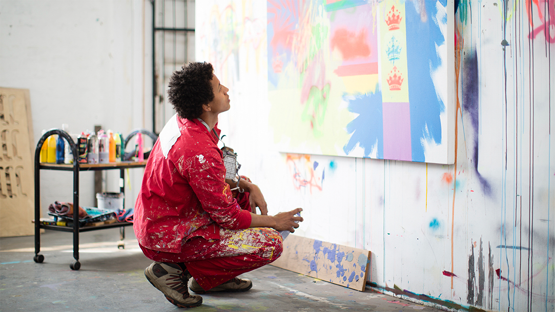 A young creative artist is working with graffiti style spray paints in his studio space