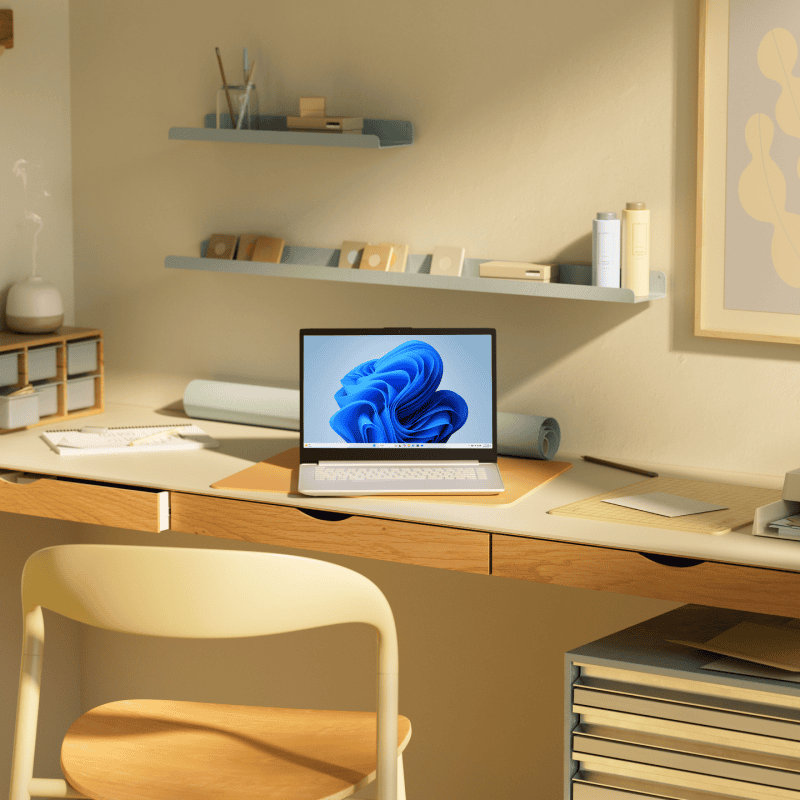 An open laptop with the blue bloom screen sitting on a desk with a chair, drawers, and shelves