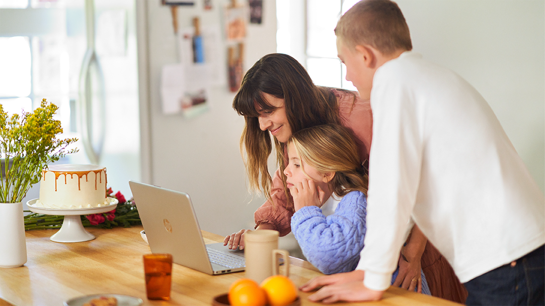 Adult female mother and female and male child using laptop in kitchen