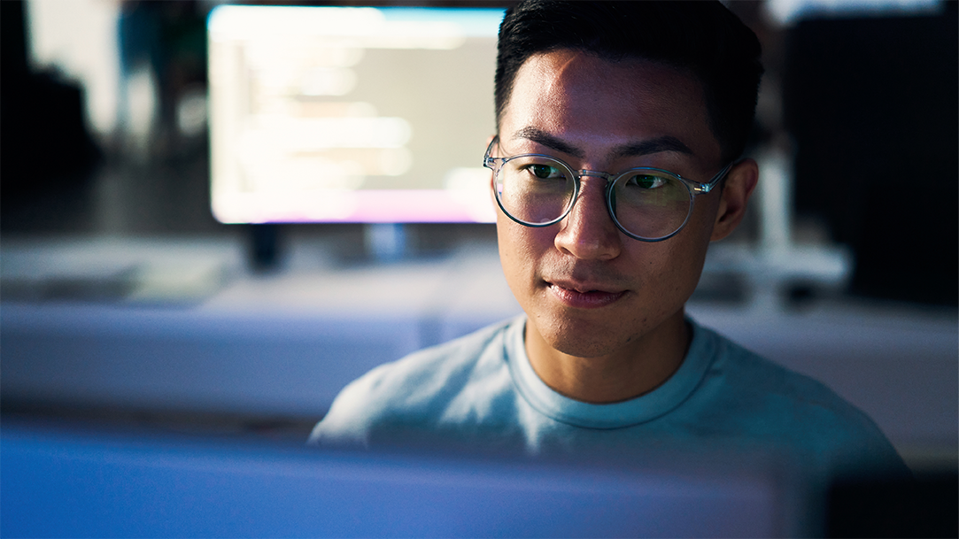 An Asian man looking at a computer screen in a work environment