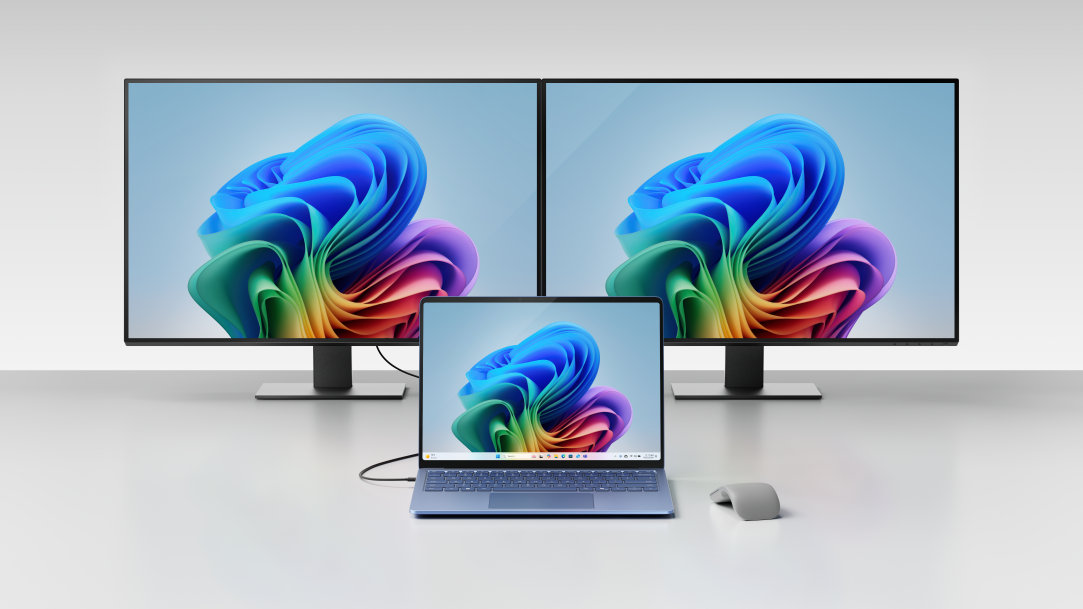 An image of a Surface Laptop, Copilot+ PC with a Surface Arc Mouse and two large monitors