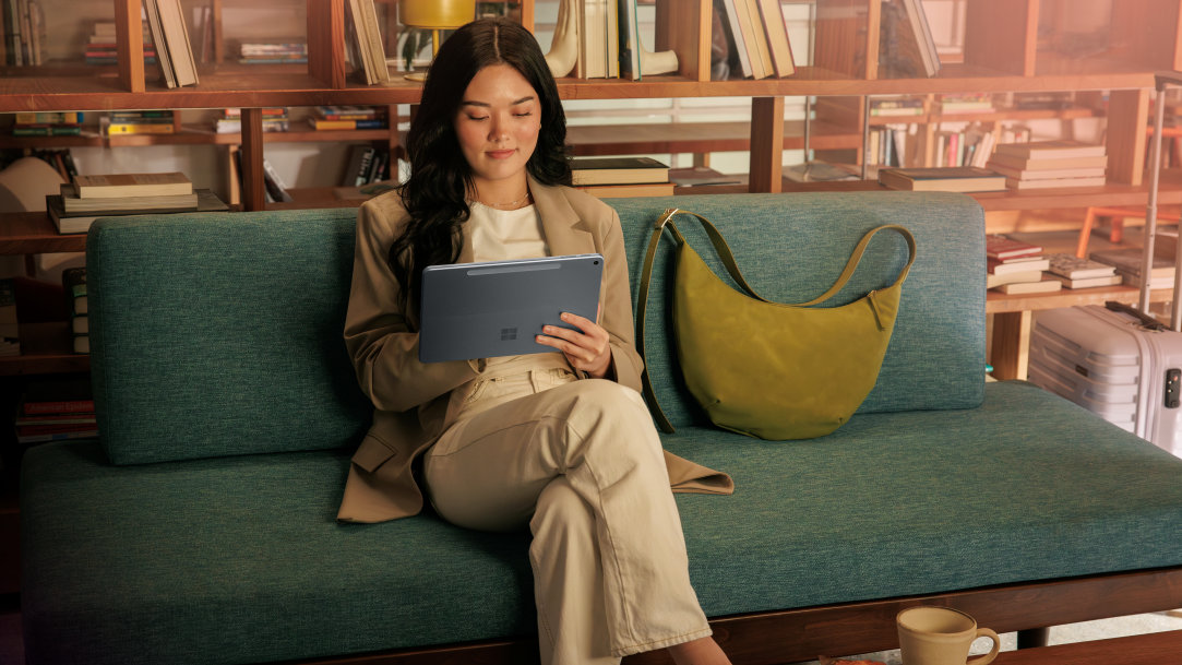 An image of a female digital nomad sitting on a couch in a coffee shop using a Surface Pro