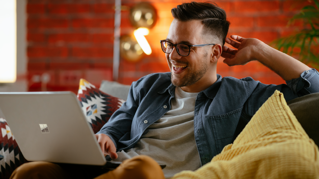 An image of a man using a laptop on a sofa