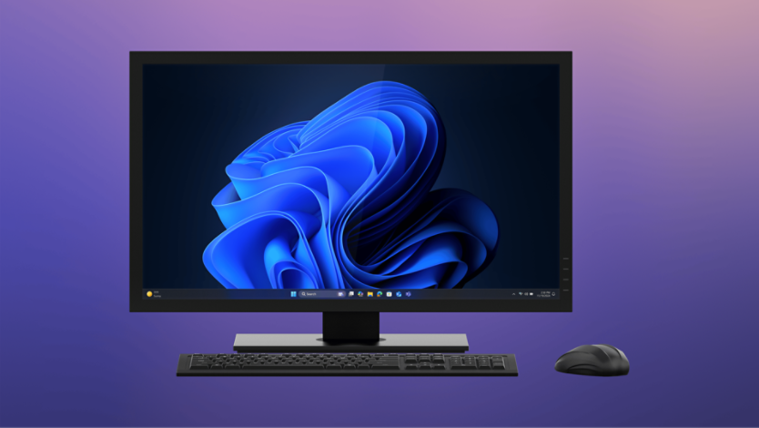 An all-in-one device displaying the Windows 11 screen with the Microsoft blue bloom on home screen.  A keyboard is placed in front of the monitor, with a mouse to the right, all set against a purple-to-pink gradient background. 
