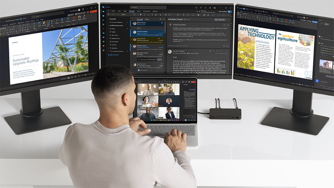 Image of a man collaborating on a Copilot+ PC Surface Laptop on a Teams call with 3 monitors