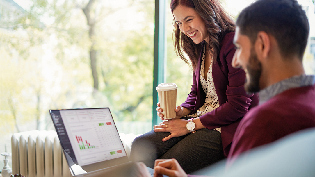 Two smiling coworkers looking at productivity apps on a Windows computer