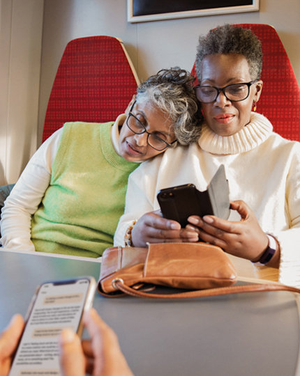 Two people wearing glasses sitting at a table, looking at a phone
