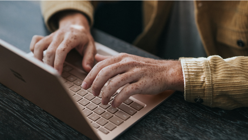 Man in yellow dress shirt using Microsoft Surface Laptop
