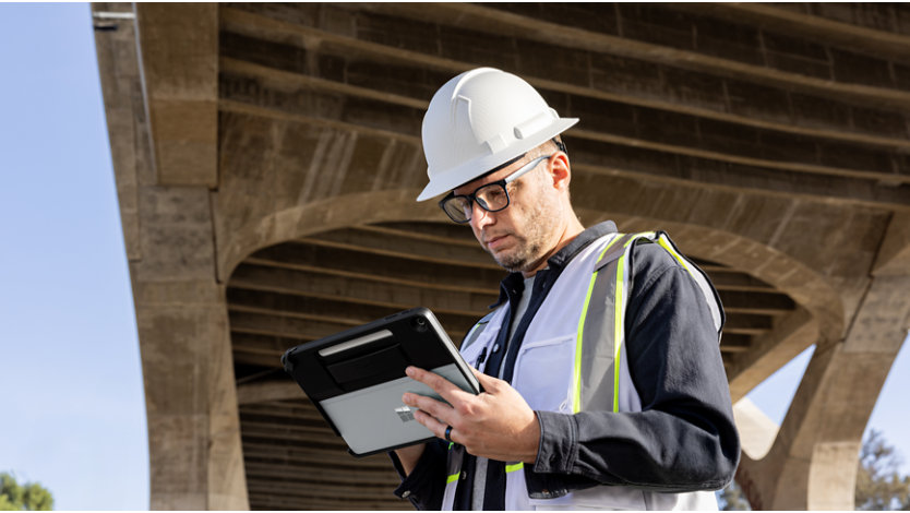 Frontline worker under bridge holding Surface Pro