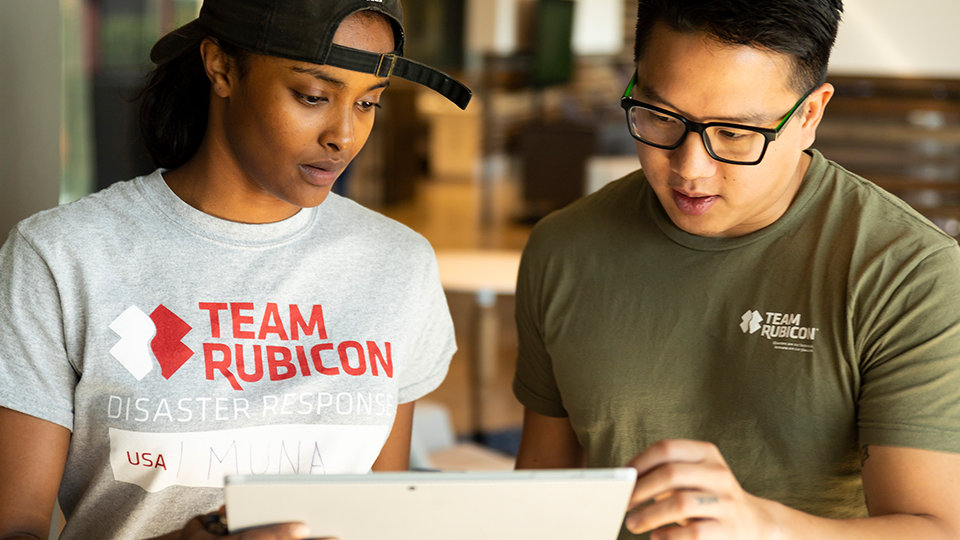 Team Rubicon crew members looking at a tablet together.